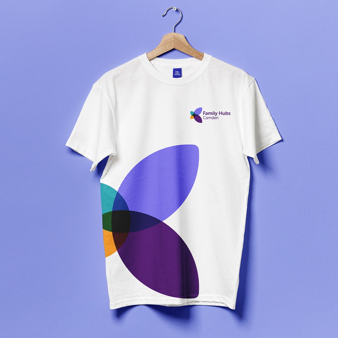 White branded t-shirt for Camden Family Hubs featuring a bold overlapping petal motif in shades of teal, orange, purple and black. The vibrant, modern design supports a warm, inclusive brand strategy for services supporting families and communities.