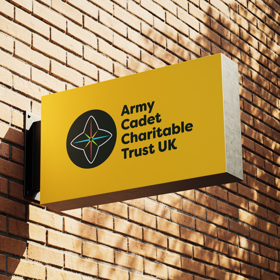 Exterior signage for Army Cadet Charitable Trust UK featuring the charity’s bold star emblem and confident black logotype on a bright yellow background—part of a refreshed brand strategy designed for visibility and impact.