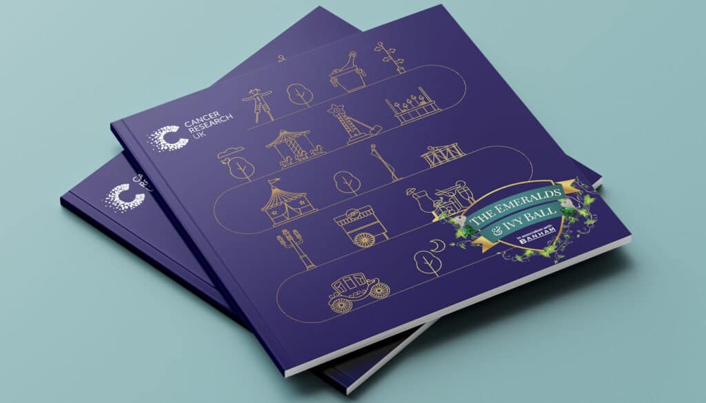 Close-up of a dark blue event programme designed for Cancer Research UK’s Emeralds & Ivy Ball, featuring delicate gold line illustrations of fairground attractions and a leafy crest motif on the cover. The design captures a sense of celebration and fundraising purpose