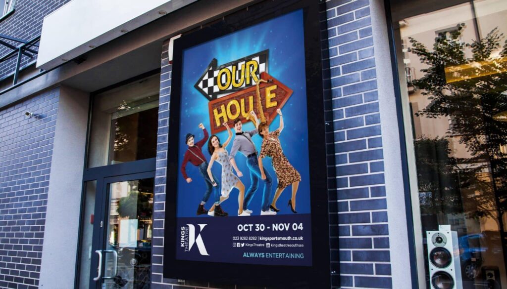 Outdoor poster for ‘Our House’ musical at Kings Theatre, featuring cast members dancing in front of a colourful dual arrow sign with show details.