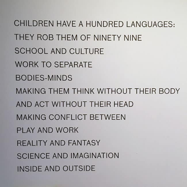 Wall text display reading a poetic statement about the lost languages of childhood and the conflict between learning and imagination.