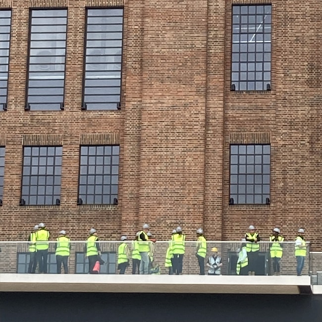 Construction workers in high-visibility jackets outside Battersea Power Station.