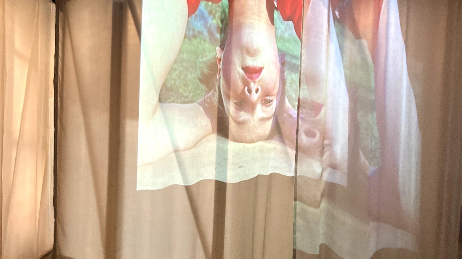 Art installation with a photograph of a woman projected upside-down onto semi-transparent fabric panels.