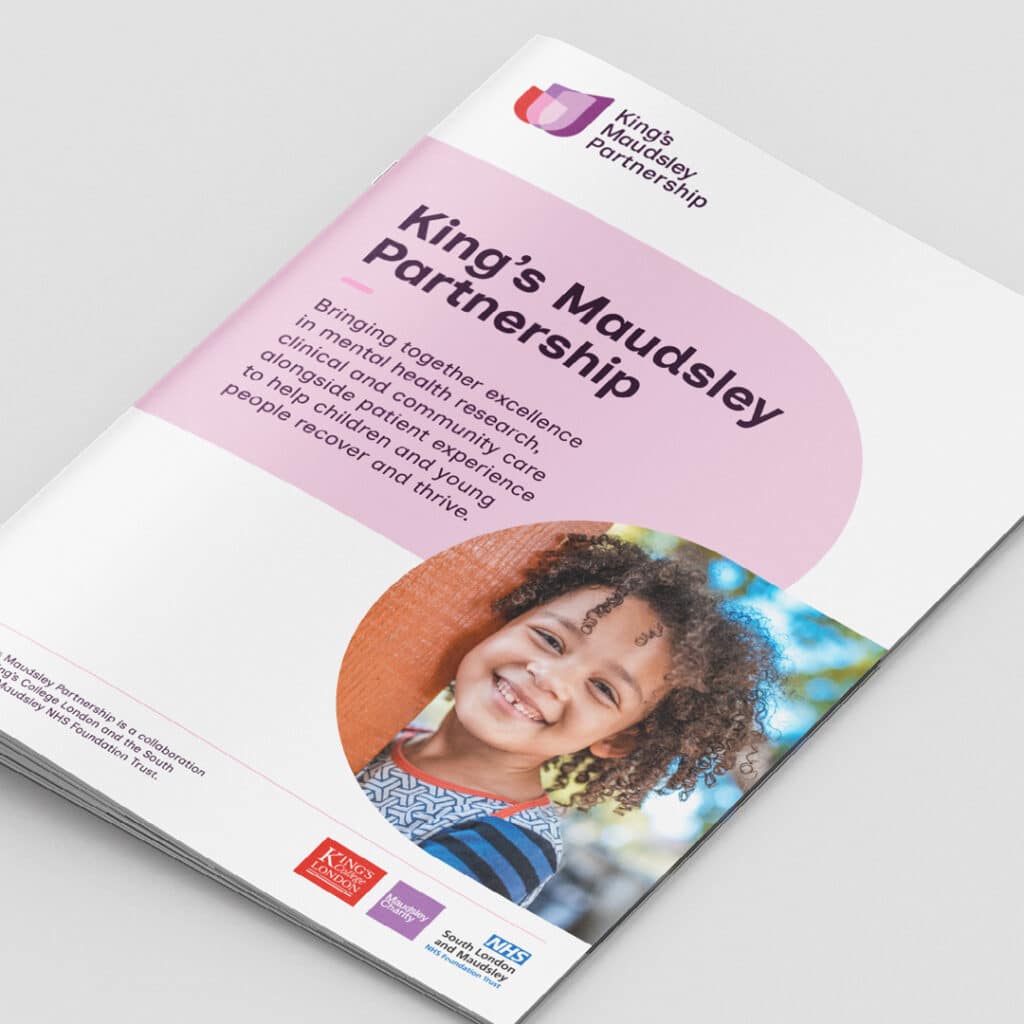 A printed brochure for the King’s Maudsley Partnership, featuring its pink and white brand design. The cover headline reads “King’s Maudsley Partnership” with supporting text about bringing together mental health research and care. The cover also shows a smiling child leaning against an orange wall. Logos for King’s College London, University of Oxford, and the NHS are displayed at the bottom.